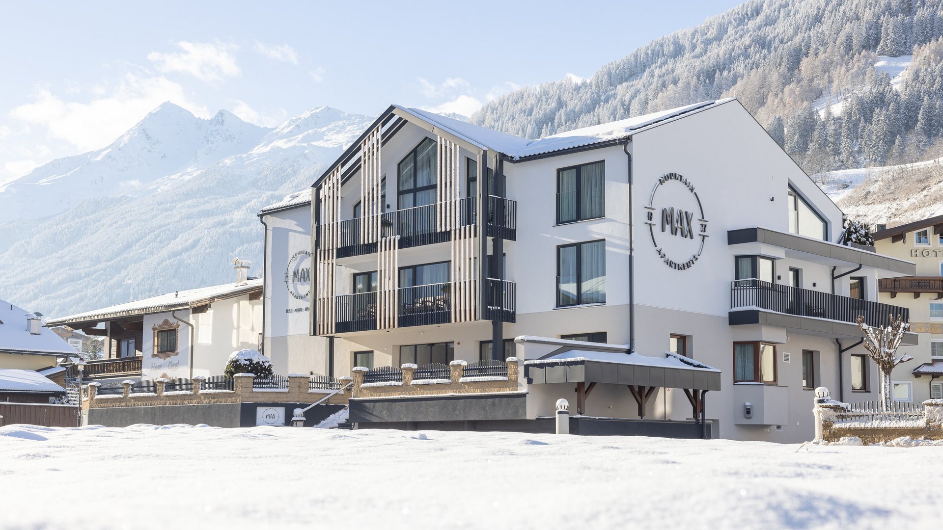 Modernes Apartmentgebäude im verschneiten Bergdorf bei Sonnenschein